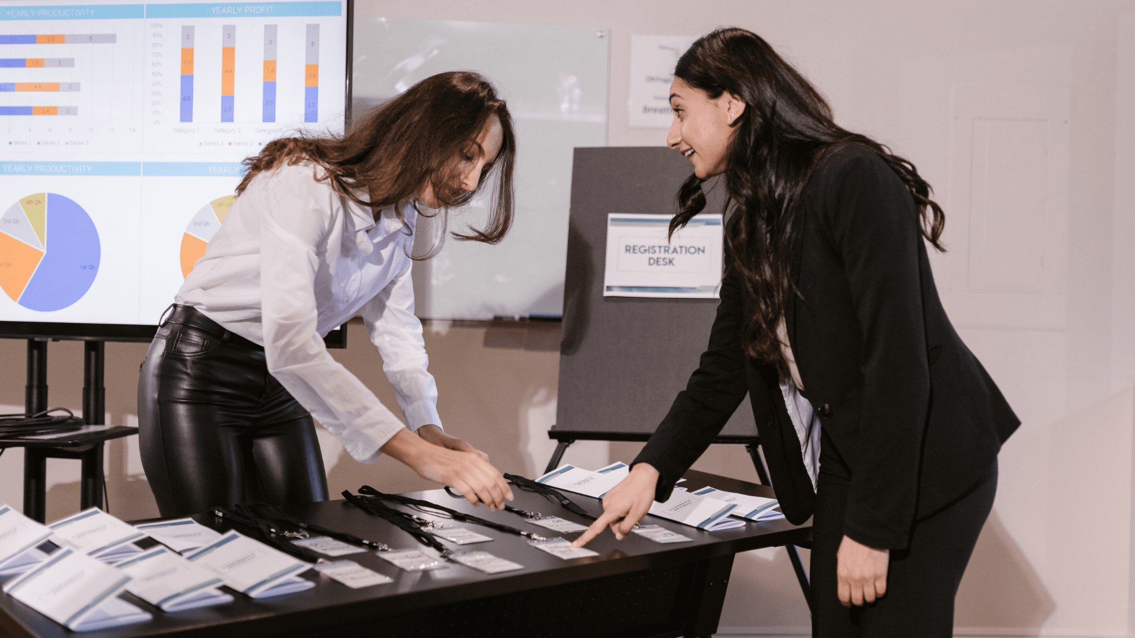 An event coordinator at the registration desk helping an attendee select their event badge.
