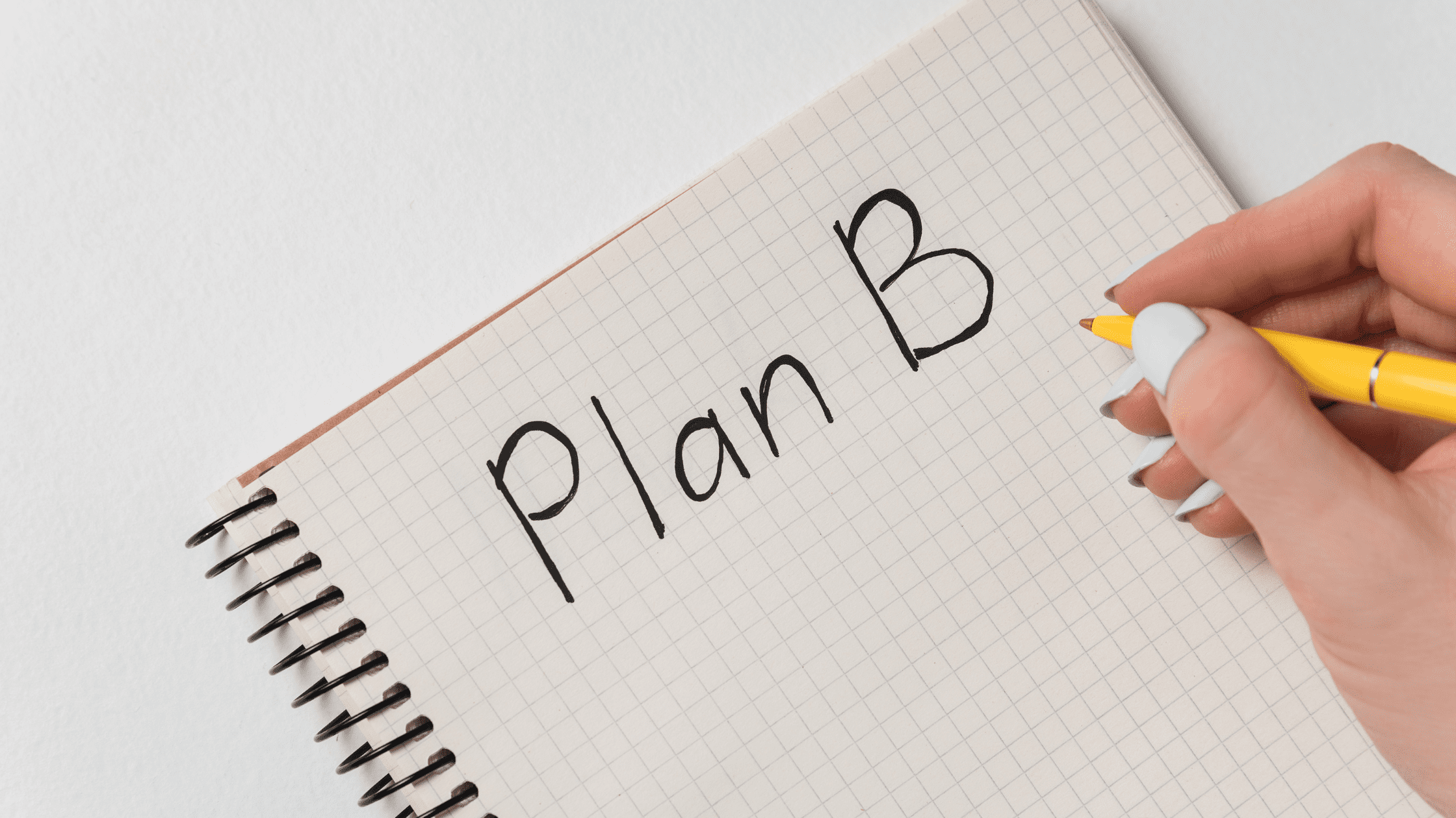 A notebook with a person writing 'Plan B,' symbolizing event contingency planning and backup strategies.