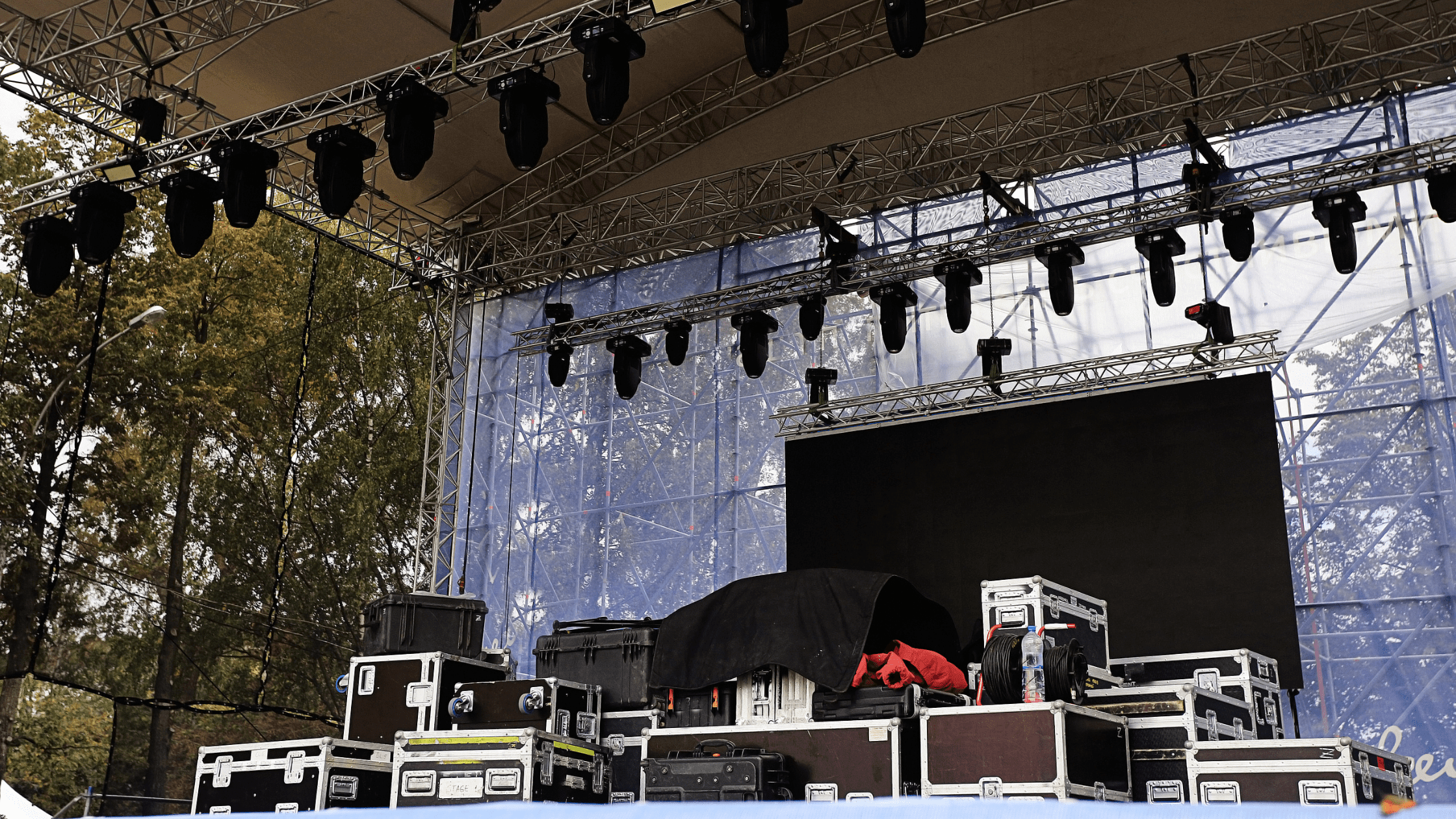 Outdoor stage load-in with various technical boxes and equipment being set up for an event.