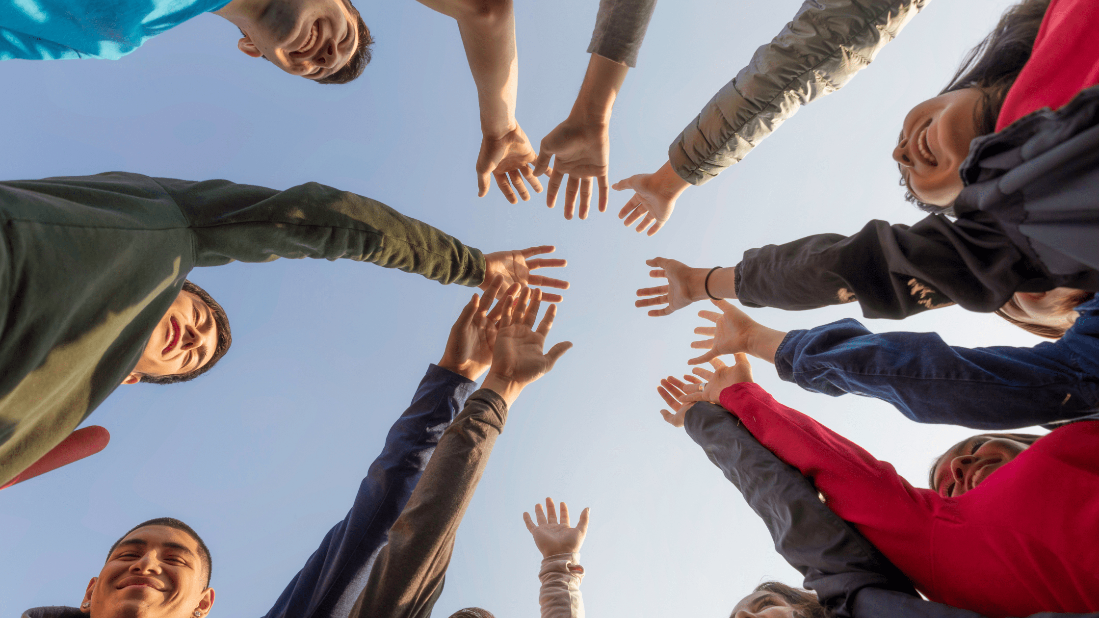 A group of people standing in a circle, smiling and holding their hands together, symbolizing event industry experts.