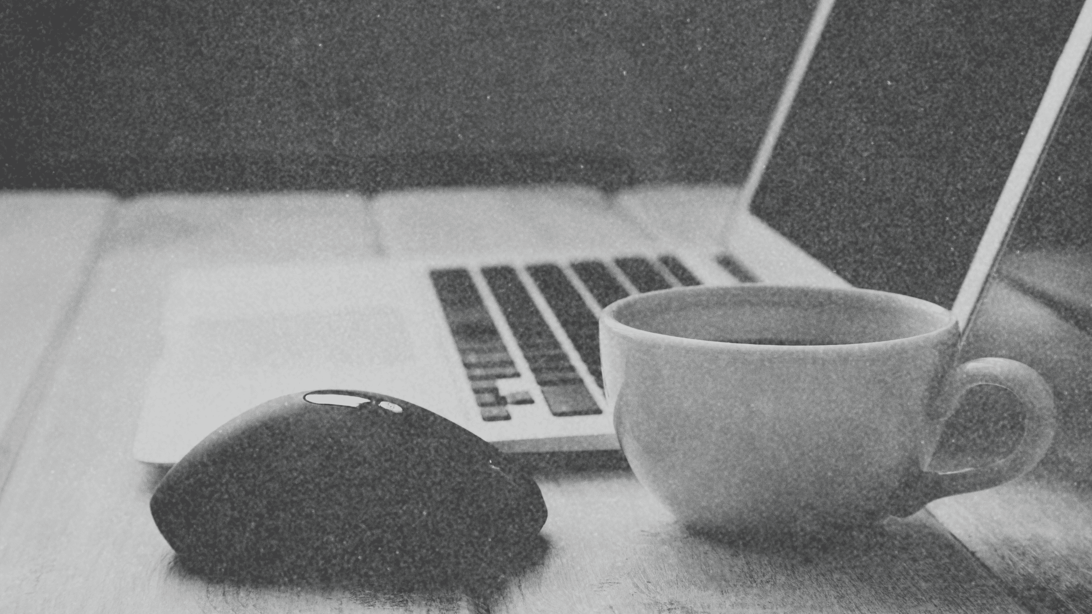 Organized desk with coffee and a computer, set up for a virtual All-Hands Meeting for events and reading blogs.