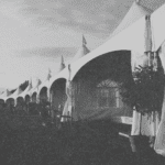 A row of outdoor event vendor tents set up at a bustling event, showcasing various services and products for attendees.